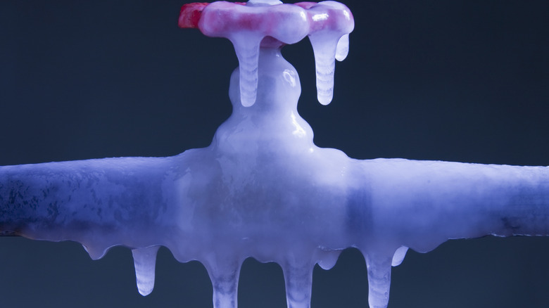 The valve connection for a pipe is completely frozen over, covered in icicles.