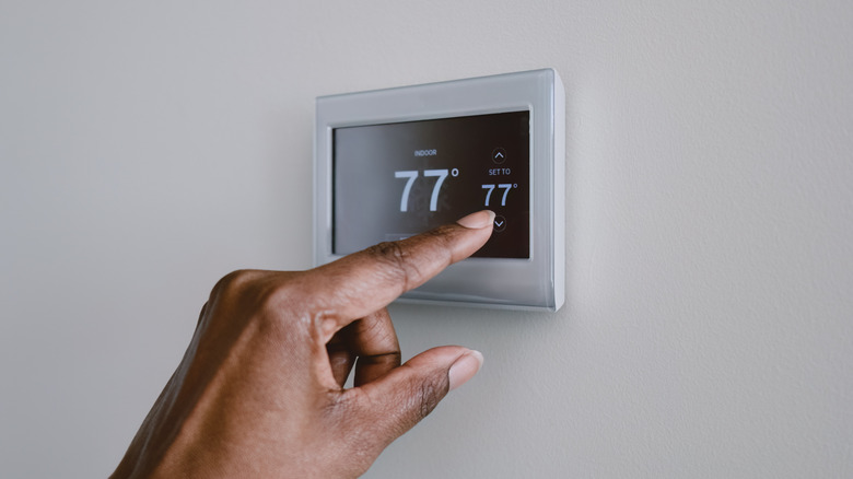 Person making adjustments to thermostat touchscreen